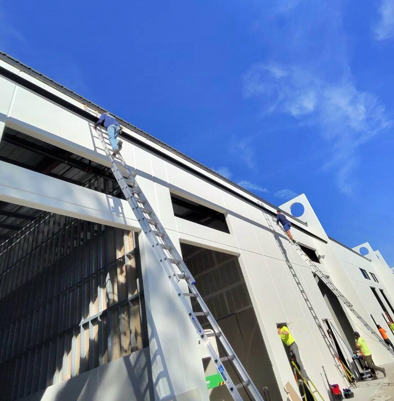 Crew installing gutters high on a large commercial building