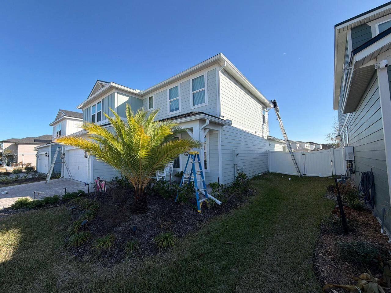 Crew installing seamless gutters on a two-story North Florida home